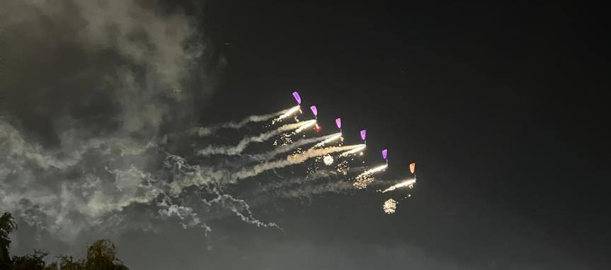 Paramotor pilots flying in formation with pyrotechnics at night